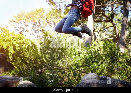 Young woman, wearing backpack, jumping in air, low section Stock Photo