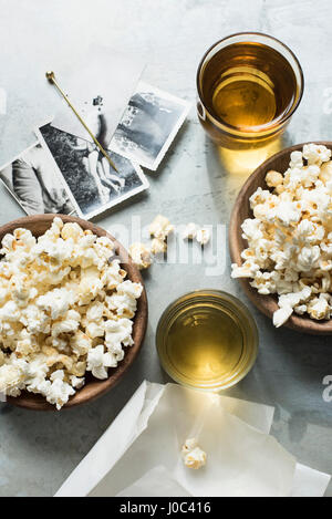 Still life of popcorn and drink, beside old black and white photographs, overhead view Stock Photo