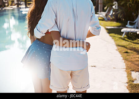 Rear mid section view of young couple embracing at poolside, Koh Samui, Thailand Stock Photo