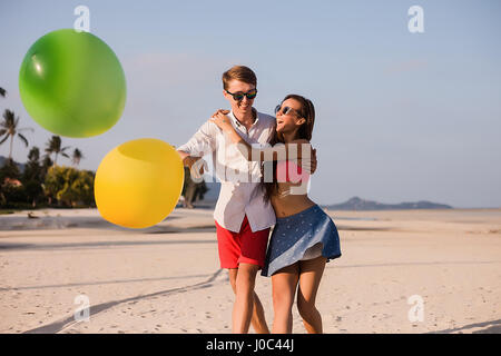 Young couple on beach playing with balloons, Koh Samui, Thailand Stock Photo