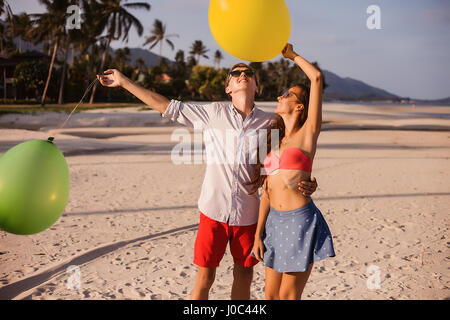 Young couple on beach looking up at balloons, Koh Samui, Thailand Stock Photo