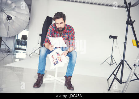 Male photographer looking at photographs in studio Stock Photo