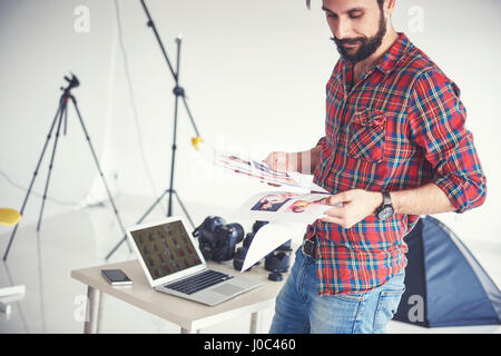 Male photographer looking at photographs from photo shoot in studio Stock Photo