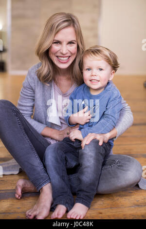 Portrait of mother and son, sitting on floor, smiling Stock Photo