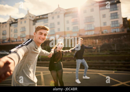 Three friends fooling around outdoors, holding hands, Bristol, UK Stock Photo