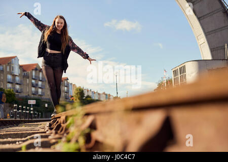 Young woman balancing on train track, low angle view, Bristol, UK Stock Photo