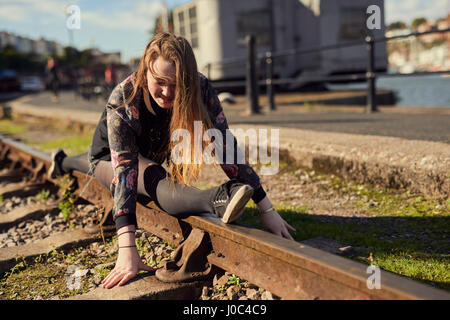 Young woman doing splits, balancing on train track, Bristol, UK Stock Photo