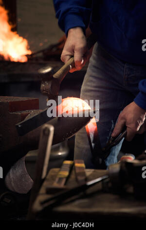 Farrier forging horseshoe on anvil Stock Photo