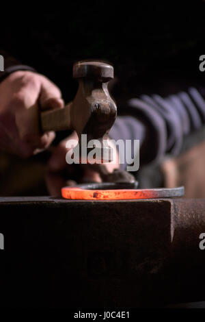 Farrier forging horseshoe on anvil Stock Photo