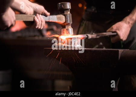 Farriers forging horseshoe on anvil Stock Photo