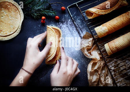 Woman making krumkake cookies, overhead view Stock Photo