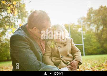 Daughter sitting on father's lap smiling Stock Photo