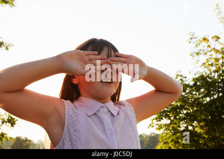 Girl covering eyes for hide and seek in park Stock Photo