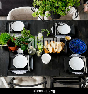 Overhead view of set table with bread slices, fresh herbs and spring onions Stock Photo