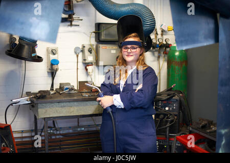 Portrait of female higher education student holding welding torch in workshop at college Stock Photo