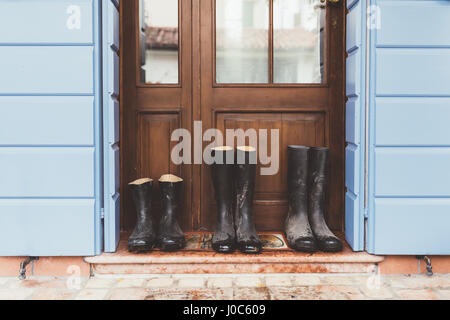 Three pairs of rubber boots on doorstep Stock Photo