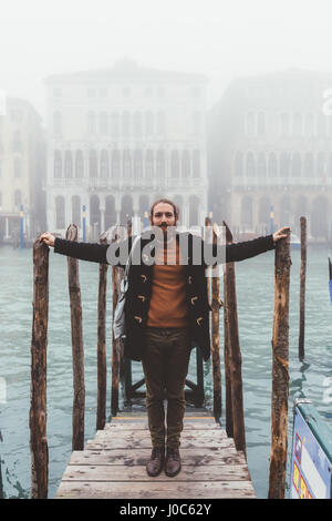Portrait of mid adult man on misty canal pier, Venice, Italy Stock Photo