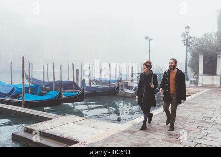 Couple strolling along misty canal waterfront, Venice, Italy Stock Photo