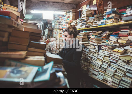 Young woman browsing in stacked book shop, Venice, Italy Stock Photo
