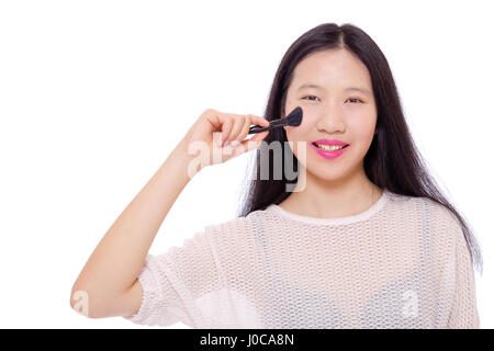 Teenage Asian girl applying makeup with a brush Stock Photo