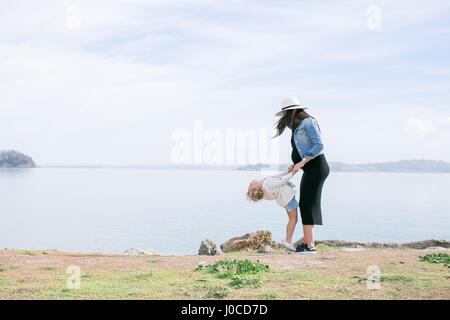 Pregnant mother playing with daughter at coast Stock Photo