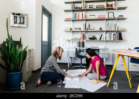 Colleagues on office floor looking at blueprints Stock Photo