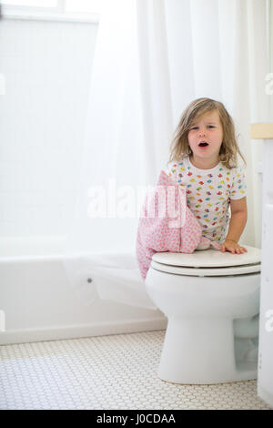 Portrait of girl with messy hair leaning against toilet Stock Photo