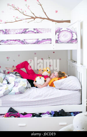 Portrait of girl lying on bunk bed with soft toys Stock Photo