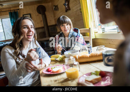 Three friends sitting around table, eating breakfast Stock Photo