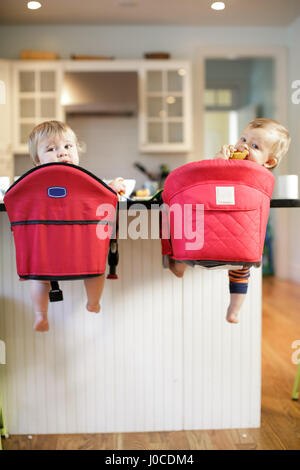 Rear view portrait of male and female toddlers looking back from kitchen counter Stock Photo