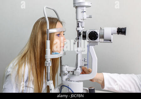 optometry concept - pretty young woman having her eyes examined by an eye doctor on a slit lamp Stock Photo