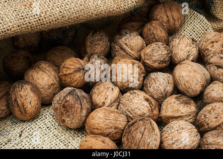 Walnuts in a burlap bag on a wooden background. Stock Photo