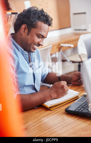 Indian man working in office and taking notes for planning Stock Photo