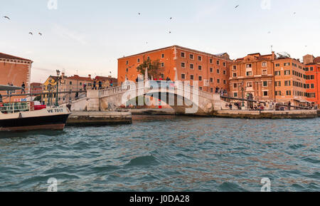 VENICE, ITALY - SEPTEMBER 23, 2016: Unrecognized people walk along waterfront bridge in Castello district with Navy Historic Museum at sunset. Venice  Stock Photo