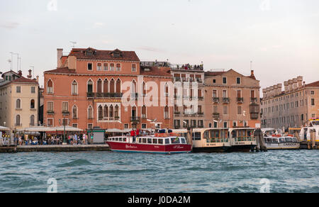 VENICE, ITALY - SEPTEMBER 23, 2016: People walk along waterfront with moored boats in Castello district and Gabrielli Hotel at sunset. Venice is one o Stock Photo