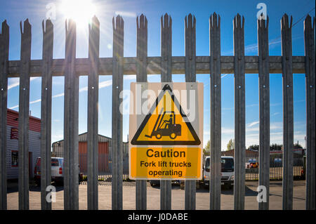 caution fork lift truck operating' sign on a fence of a goods yard Stock Photo