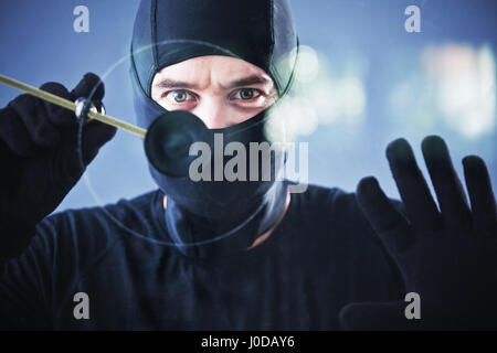 burglar in action with circular glass cutter Stock Photo