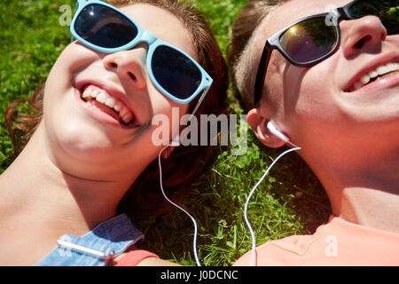 happy teenage couple with earphones lying on grass Stock Photo