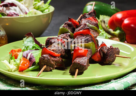Grilled beef meat and vegetable kebabs on the green plate Stock Photo