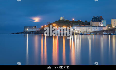 The 'pink' April full moon rises over a serene Tenby Harbour at high tide. Pembrokeshire in Wales Stock Photo