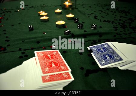 two decks of cards and a few dice set on a green felt playing table with tea lights Stock Photo