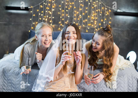 Happy young women drinking champagne at bachelorette party and smiling at camera Stock Photo
