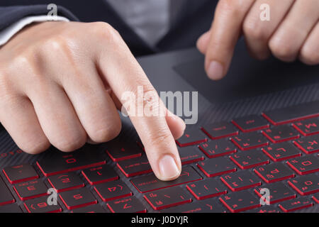 finger pushing enter button on a laptop keyboard Stock Photo