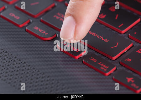 finger pushing delete button on a laptop keyboard Stock Photo