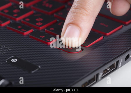 finger pushing esc button on a laptop keyboard Stock Photo