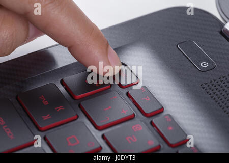 finger pushing esc button on a laptop keyboard Stock Photo