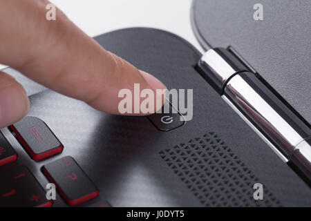 finger pushing power button on a laptop keyboard Stock Photo