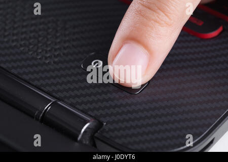 finger pushing power button on a laptop keyboard Stock Photo