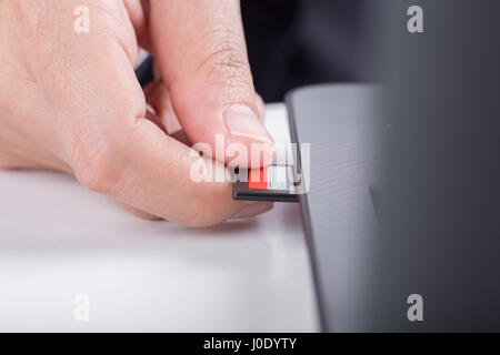 hand inserting SD card into laptop slot Stock Photo