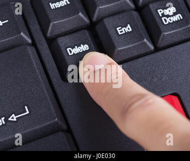 finger pushing delete button on a keyboard of computer Stock Photo